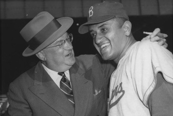 Walter O’Malley and Don Newcombe smile while shaking hands.